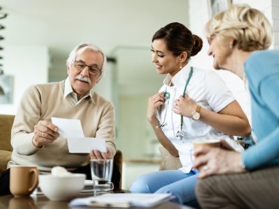 happy-mature-couple-showing-their-photos-female-doctor-who-is-visiting-them-home-focus-is-doctor